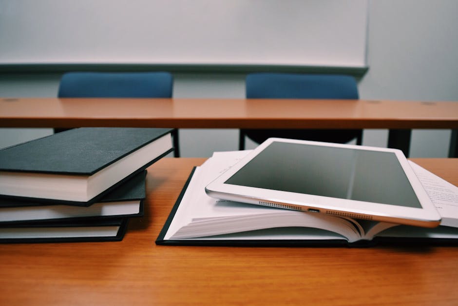 Books and a tablet on a desk in a classroom